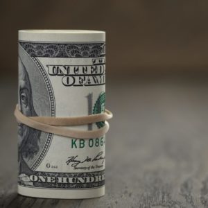 roll of old style hundred dollar bills stand on wooden table, Shallow DOF